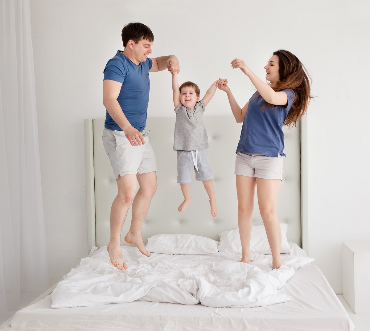 Family of three jumping on bed