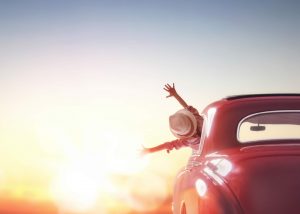 Woman happy with arms out of car enjoying the sunset