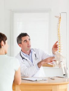 Chiropractor showing patient model of the spine
