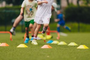 Children doing sport and running around cones
